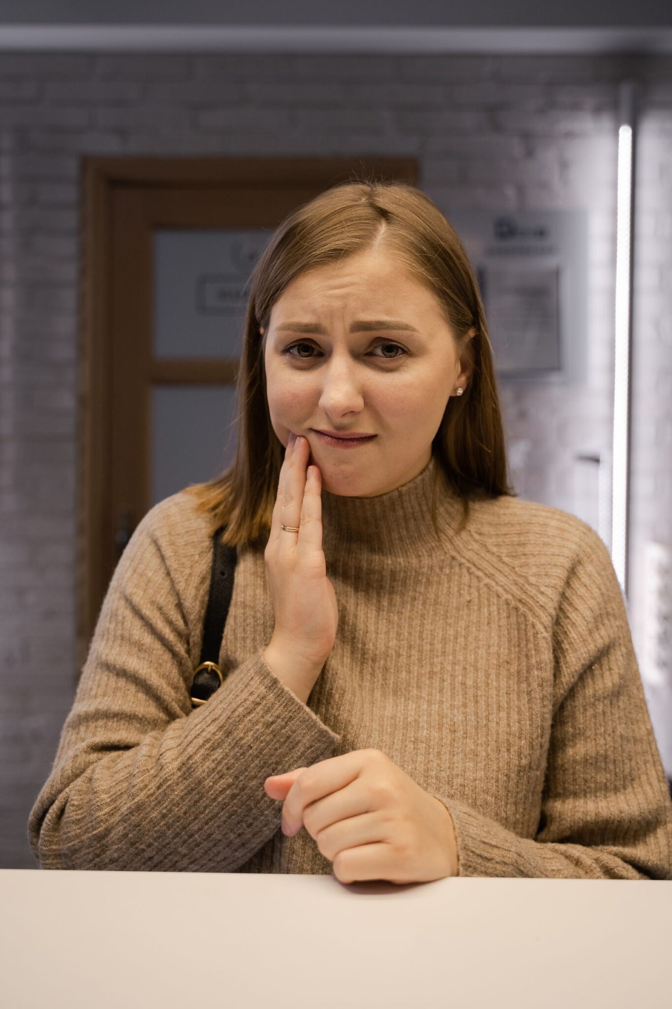 Mujer con sensibilidad dental sujetándose la mejilla por el dolor Mujer con sensibilidad dental sujetándose la mejilla por el dolor